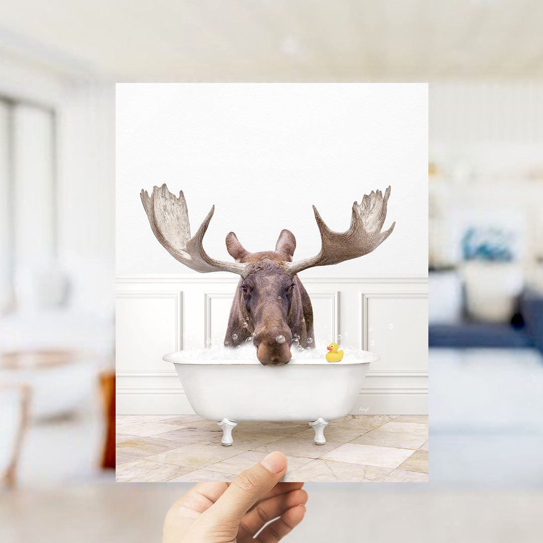 A moose with large antlers is sitting in a bathtub filled with water, with a rubber duck floating nearby.