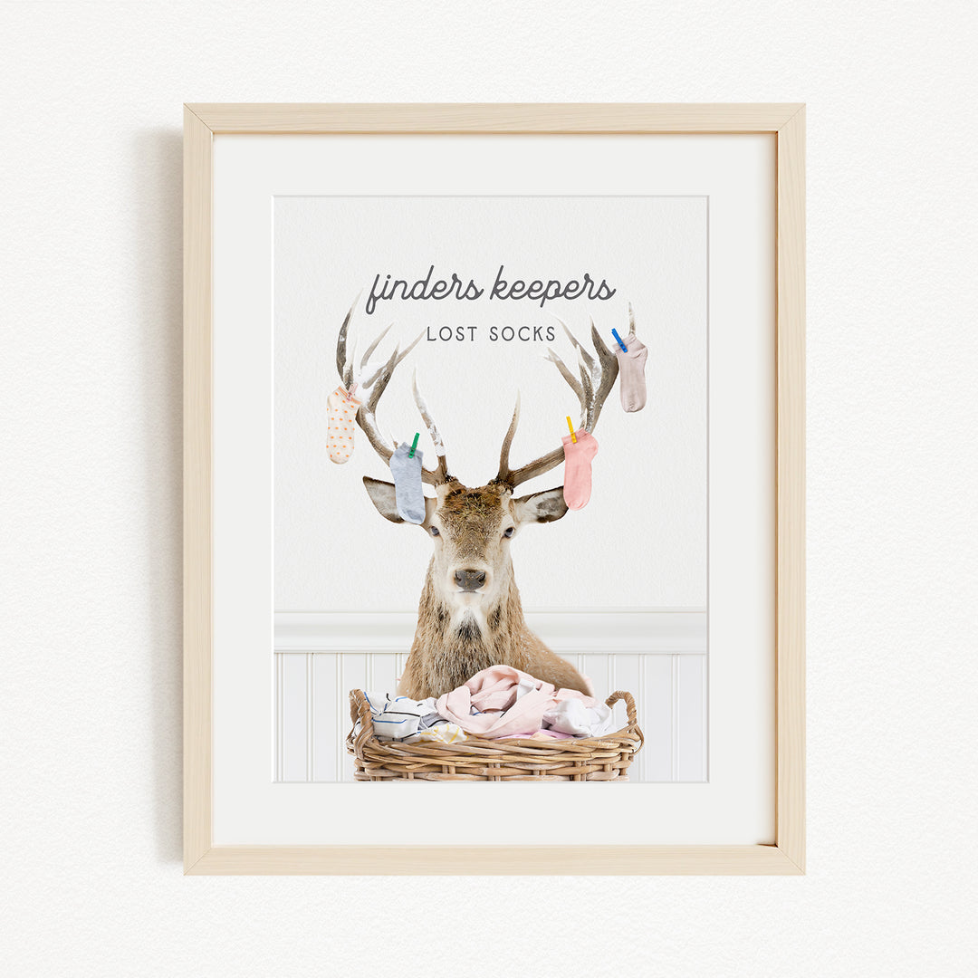 A deer with antlers sits in a basket filled with socks, with the text "finders keepers" above the deer and "lost socks" below it.