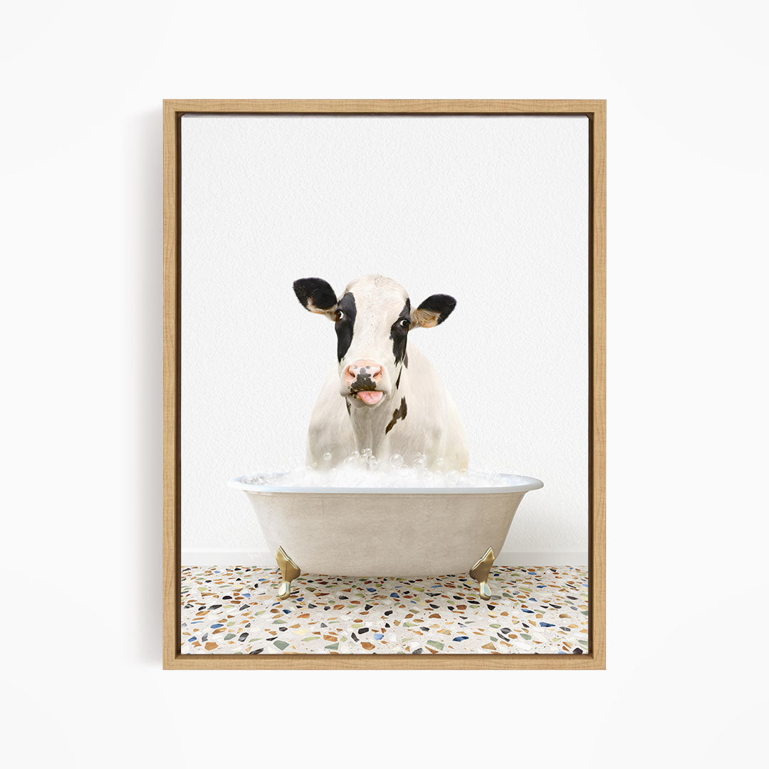 A black and white cow is sitting in a white bathtub filled with water, creating a whimsical and humorous scene.