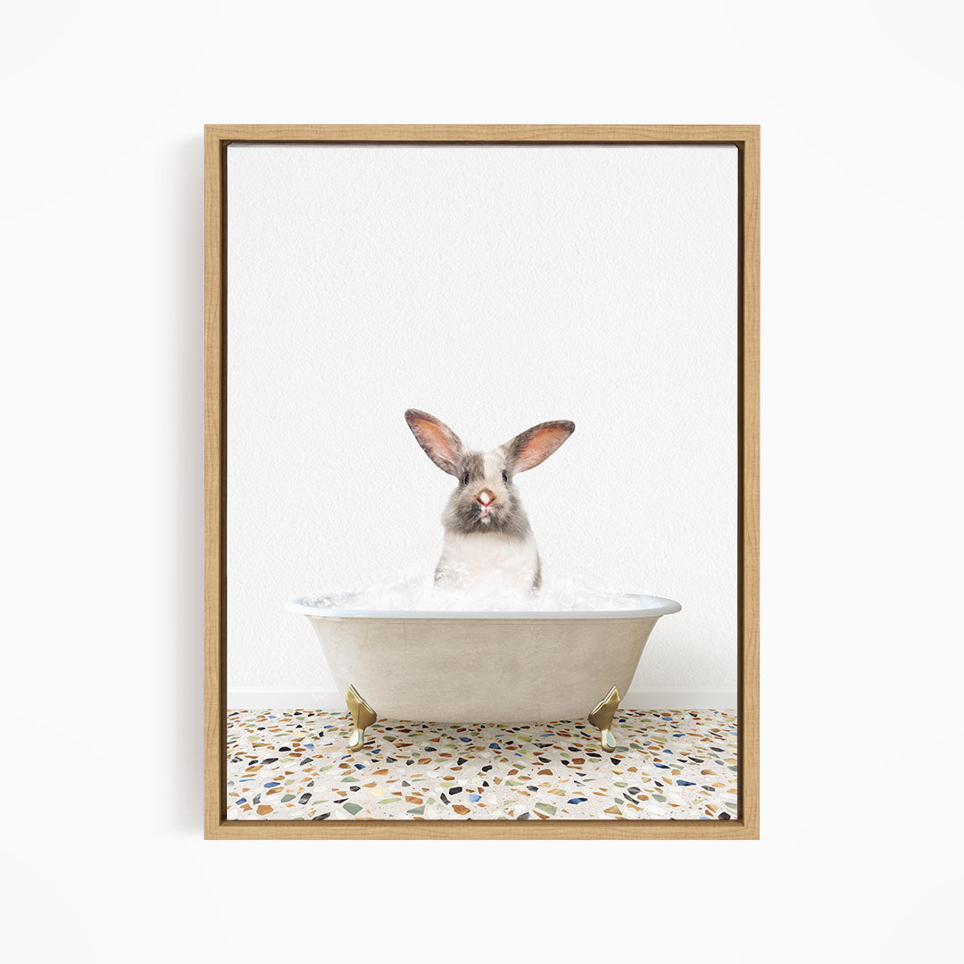 A white rabbit with brown ears is sitting in a white bathtub filled with water, looking directly at the camera.
