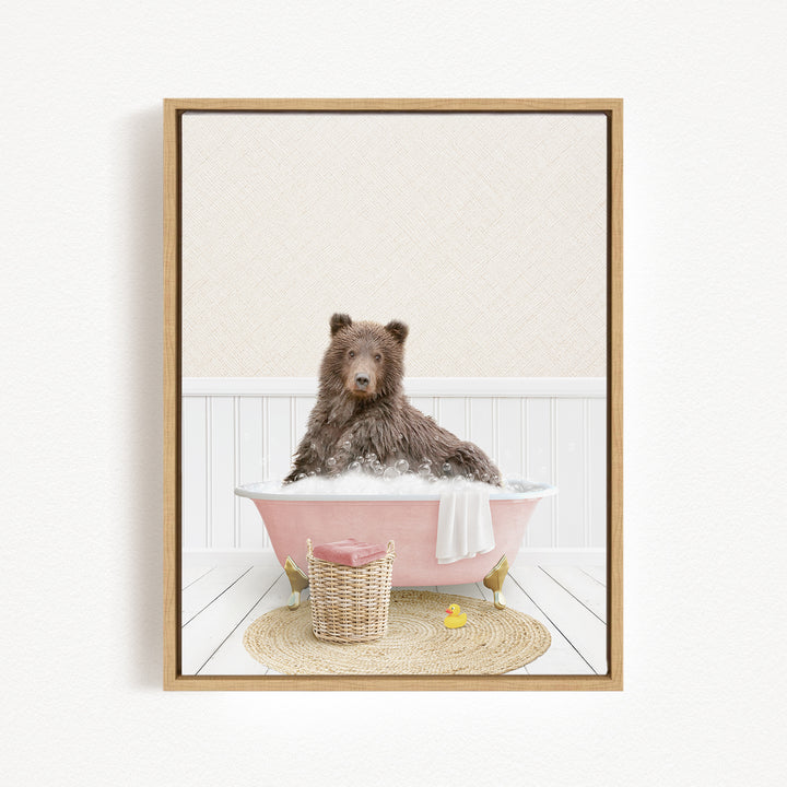 A brown bear sitting in a pink bathtub filled with bubbles, surrounded by a wicker basket and a yellow rubber duck.