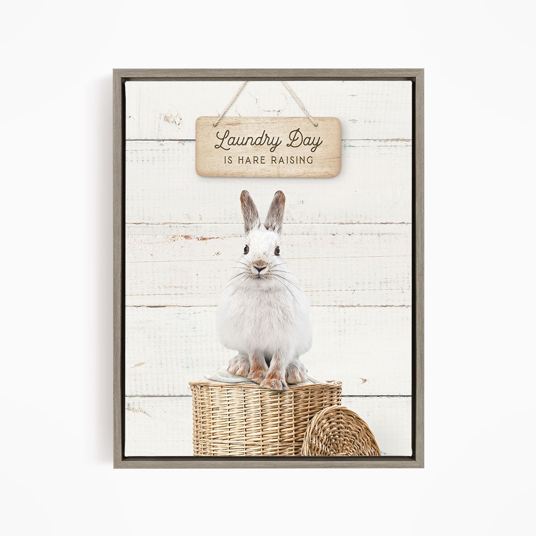 A white rabbit sitting in a wicker basket, with a wooden sign above that says "Laundry Day is Hare Raising".