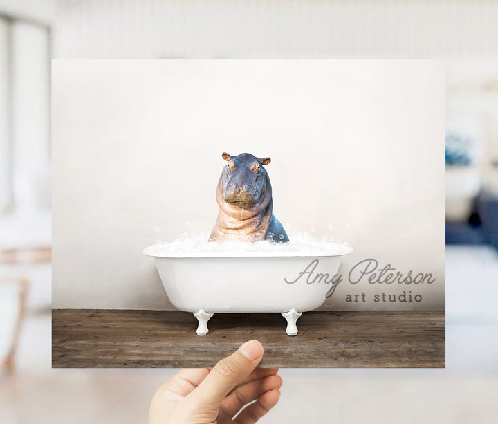 a person holding up a card with a hippo in a bathtub