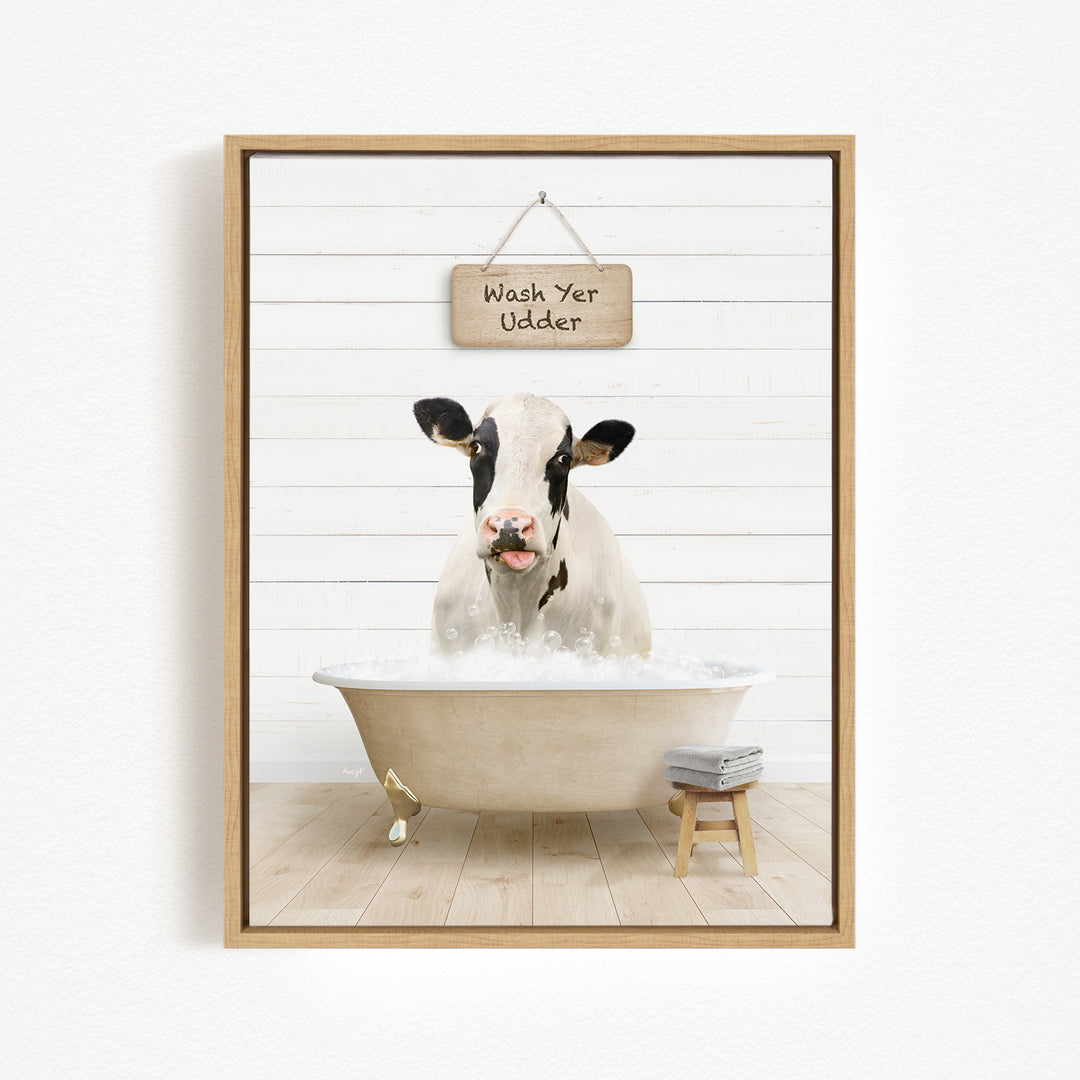 A black and white cow is sitting in a bathtub filled with water, with a sign above it that says "Wash Your Udders".