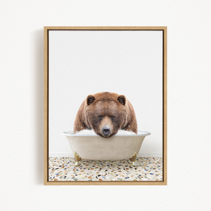A brown bear is sitting in a white bathtub, with its head submerged in the water, creating a playful and whimsical scene.