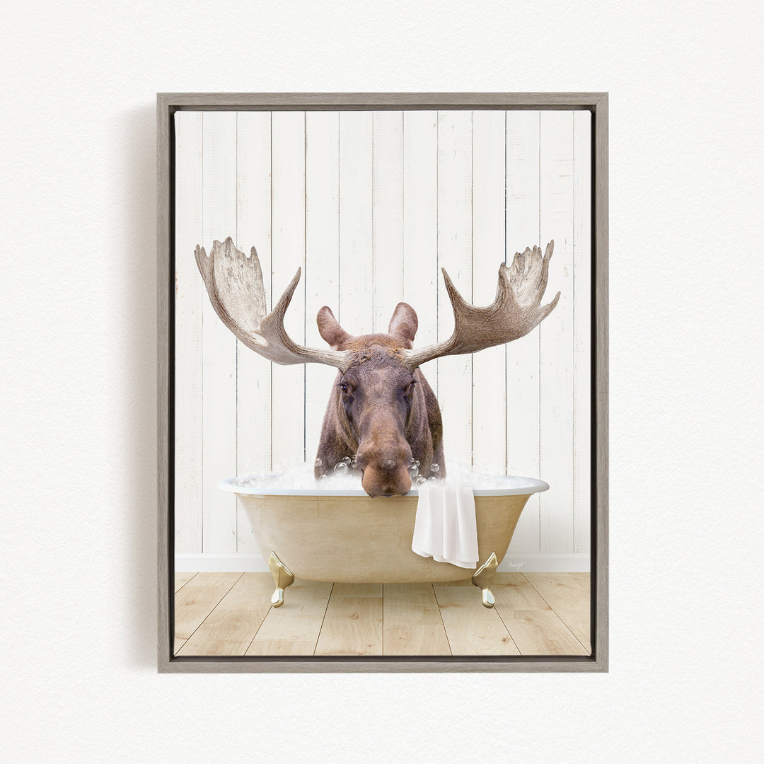 A moose with large antlers is sitting in a bathtub, appearing to enjoy the bath.