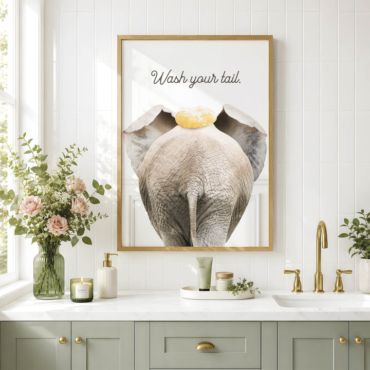 a bathroom with a framed poster of an elephant on the wall, a vase of flowers, and a sink with a green cabinet below it.