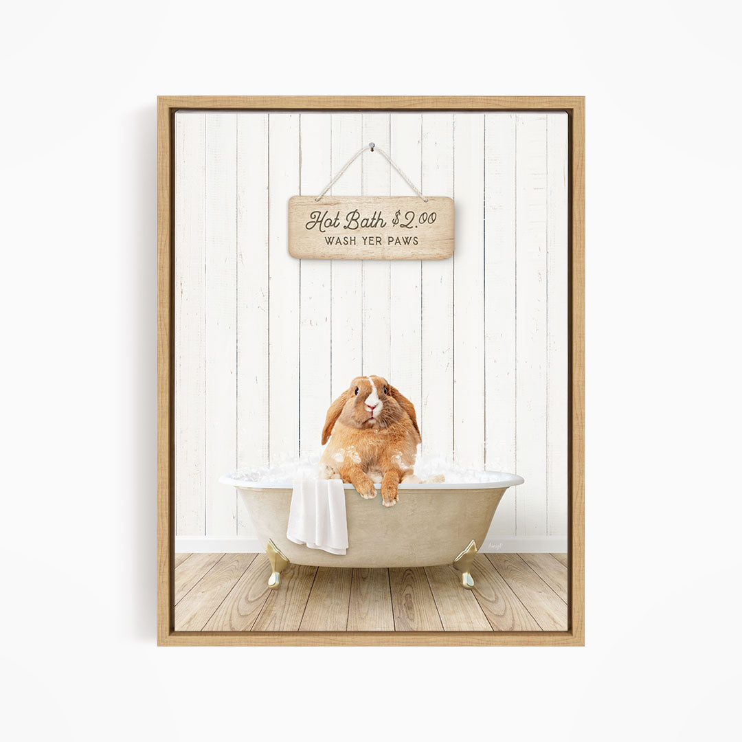 A wooden sign hangs above a white bathtub, which is occupied by a brown rabbit sitting and enjoying a bath.