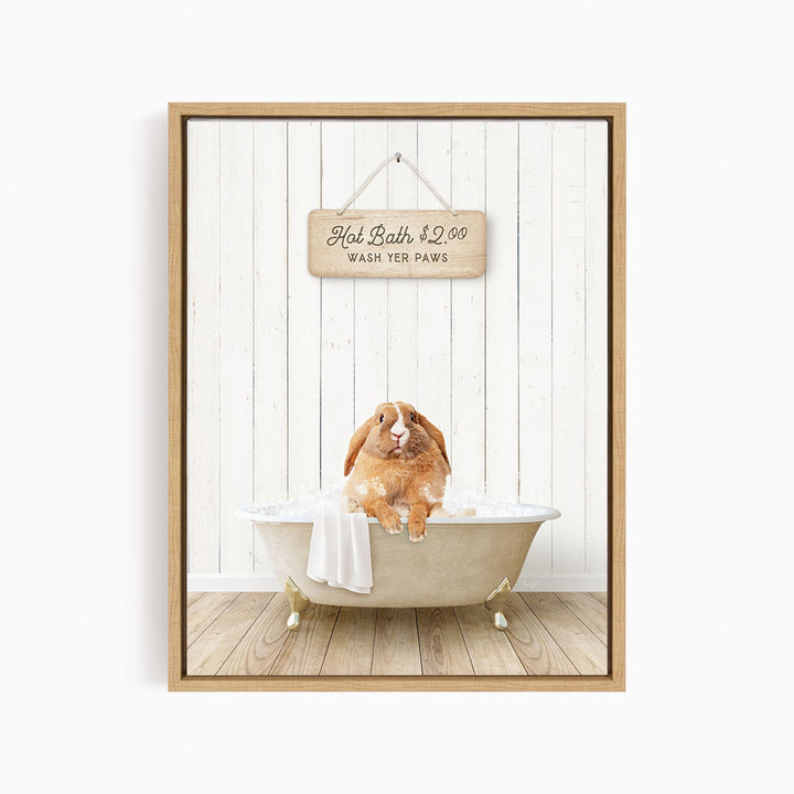 A wooden sign hangs above a white bathtub, which is occupied by a brown rabbit sitting and enjoying a bath.