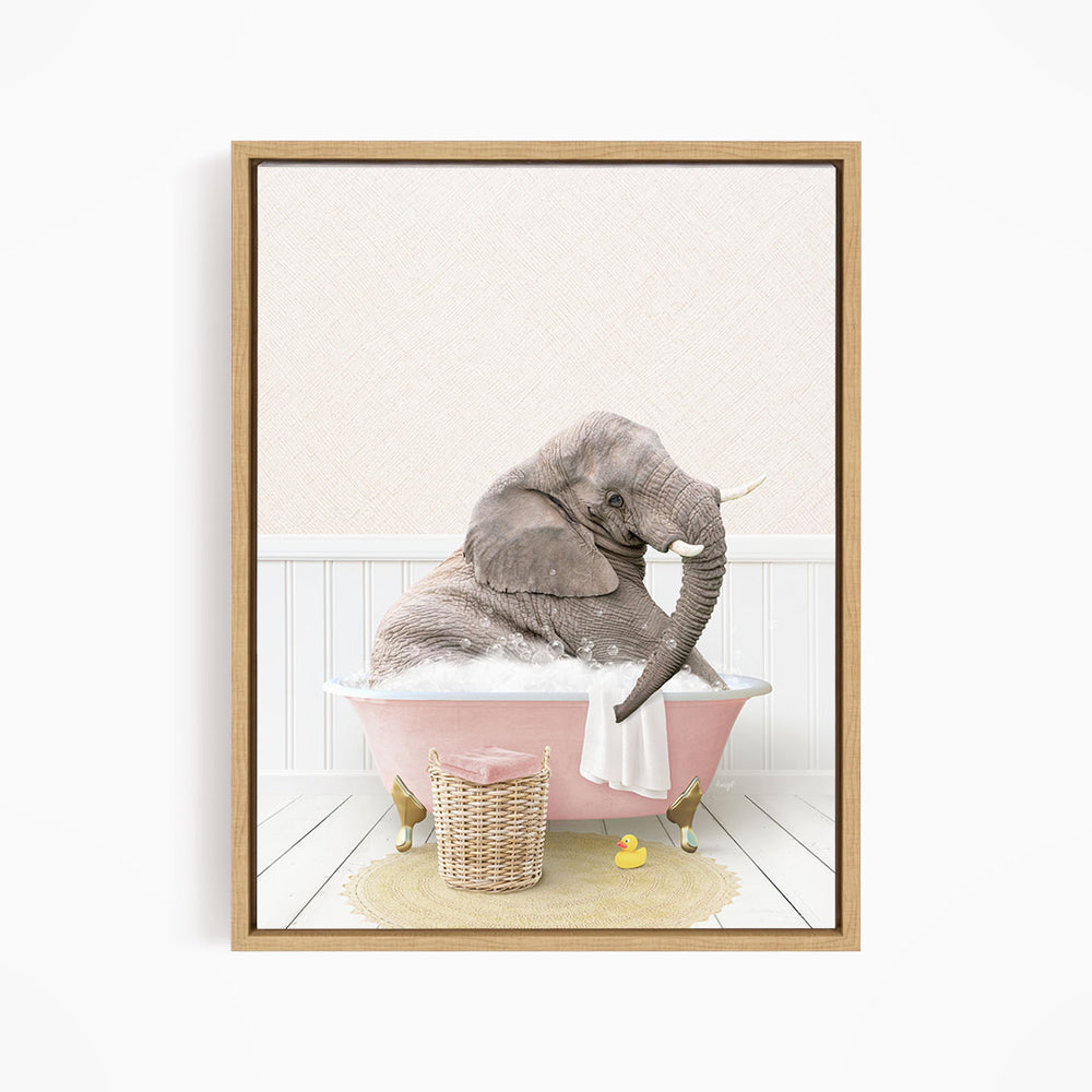 A gray elephant is sitting in a pink bathtub filled with water, surrounded by a yellow rubber ducky and a basket of bath toys.