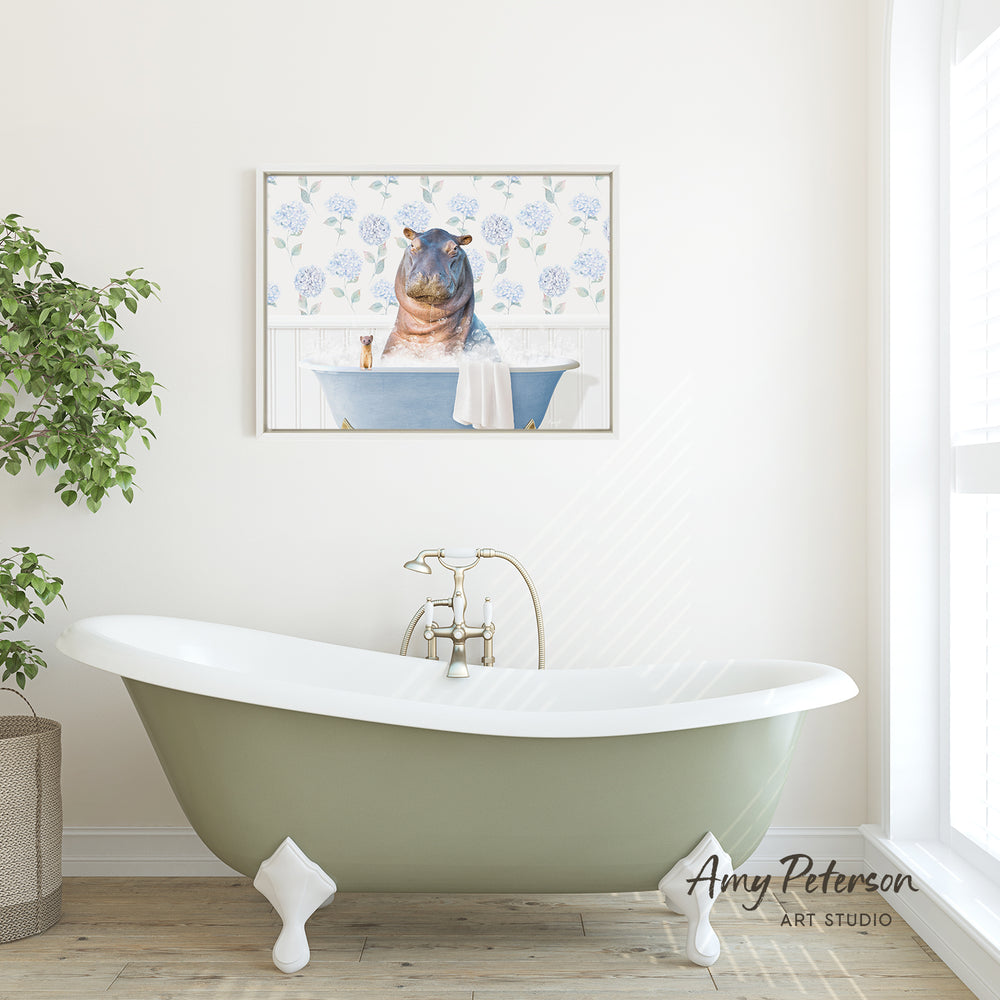 A green clawfoot bathtub with a framed image of a hippopotamus sitting in it, set against a white wall with a window and a potted plant.