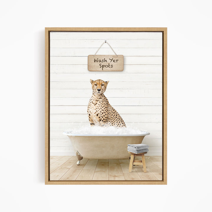 A cheetah sitting in a bathtub filled with water, with a sign above that says "Wash Yer Spots".