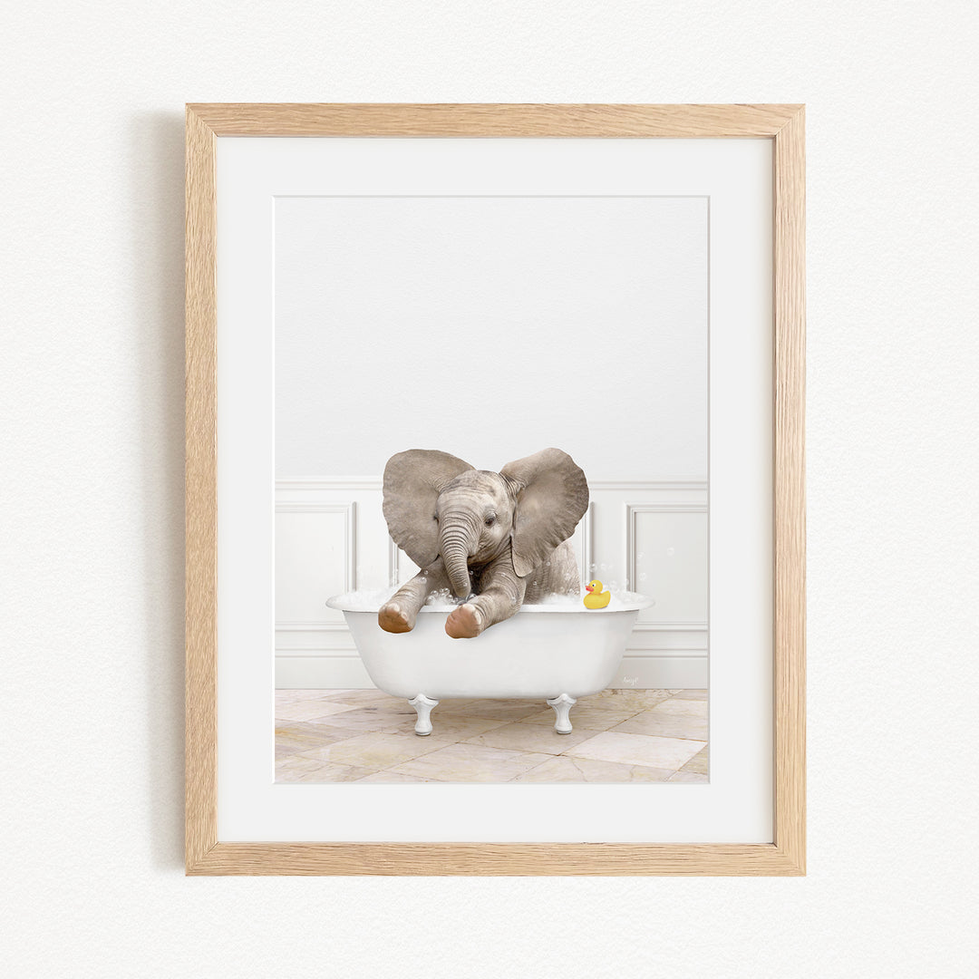 A baby elephant sitting in a white bathtub, with a yellow rubber duck floating nearby.