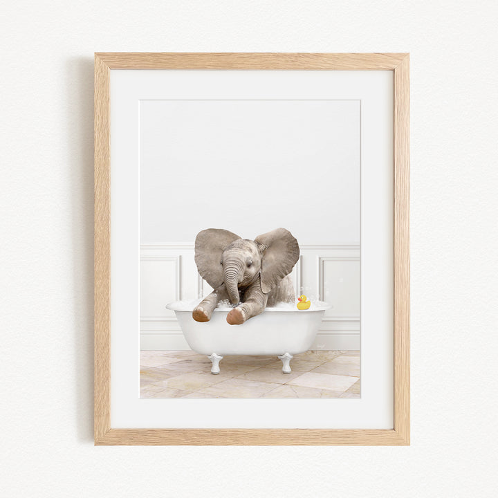 A baby elephant sitting in a white bathtub, with a yellow rubber duck floating nearby.