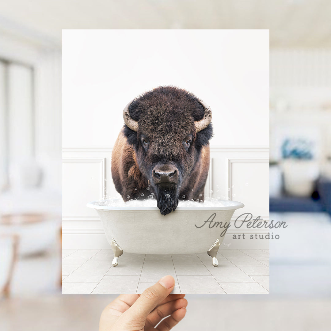 a person holding up a picture of a bison in a bathtub