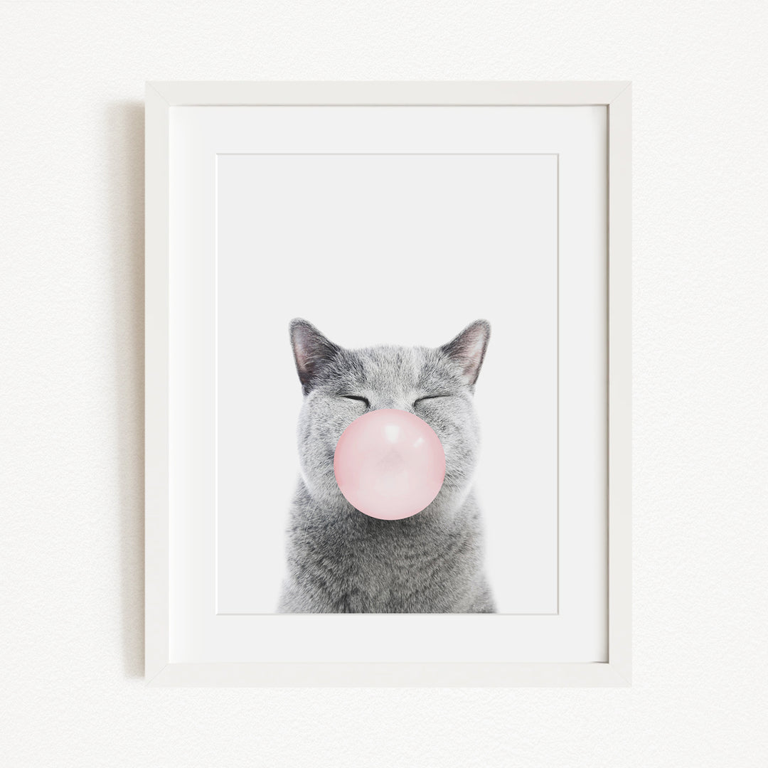 A gray cat with its eyes closed and a pink bubble blowing in its mouth, creating a whimsical and playful scene.