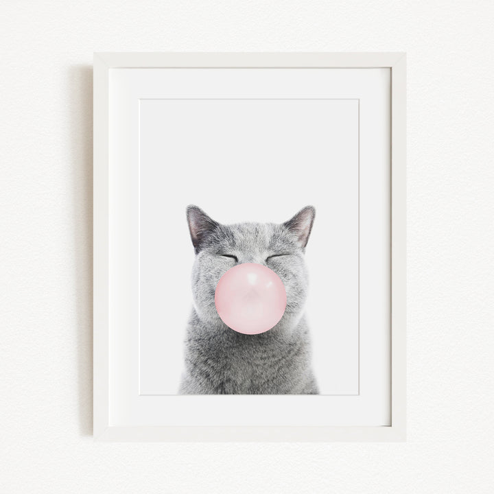 A gray cat with its eyes closed and a pink bubble blowing in its mouth, creating a whimsical and playful scene.