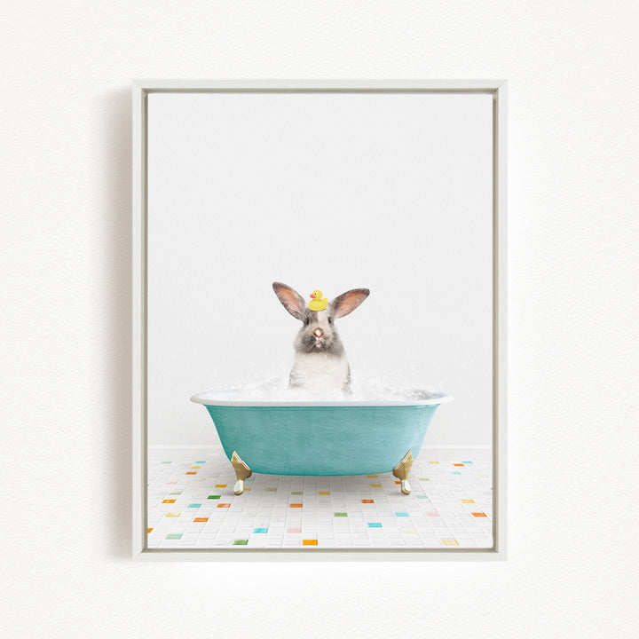 A gray and white rabbit sitting in a blue bathtub filled with water, wearing a yellow hat.