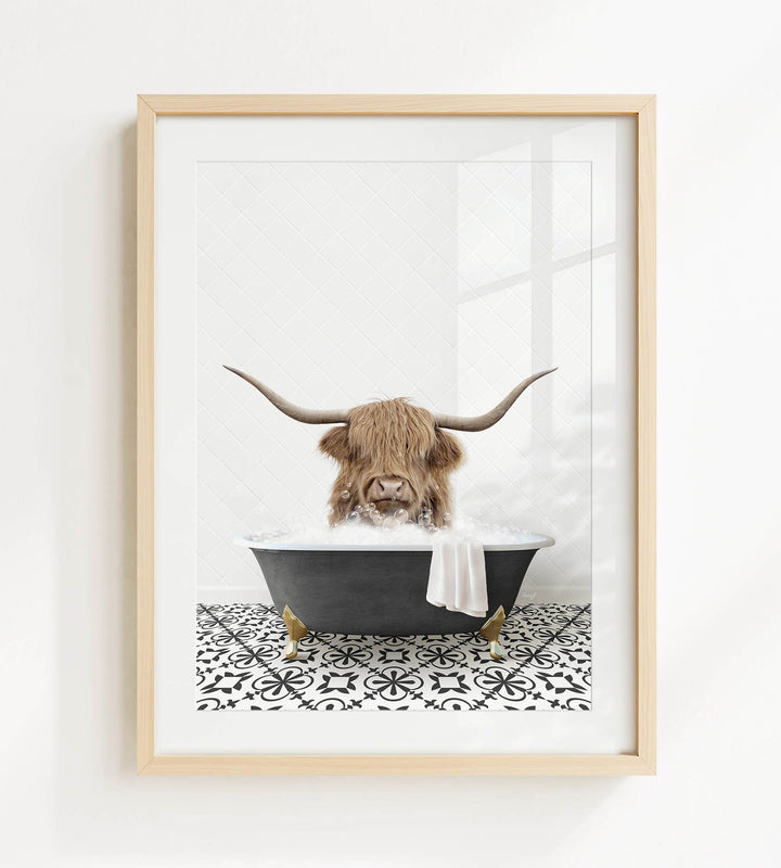 A framed image depicting a Highland cow with long horns sitting in a bathtub filled with water and bubbles.
