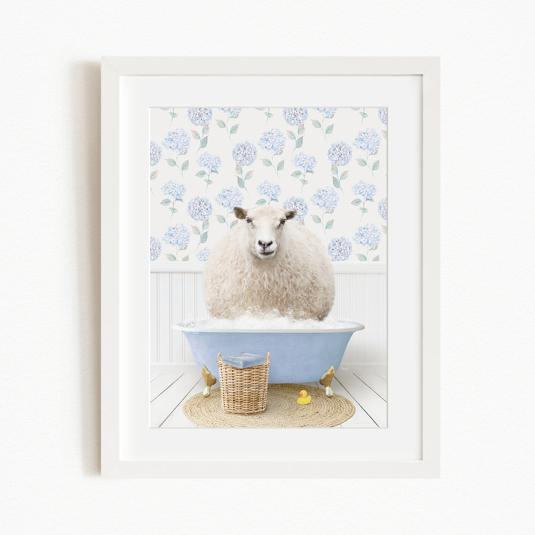 A fluffy white sheep sits in a blue bathtub filled with bubbles, surrounded by a wicker basket and yellow rubber ducks.
