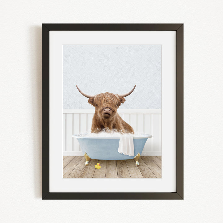 A brown cow with long horns is sitting in a blue bathtub filled with water, surrounded by yellow rubber duckies.