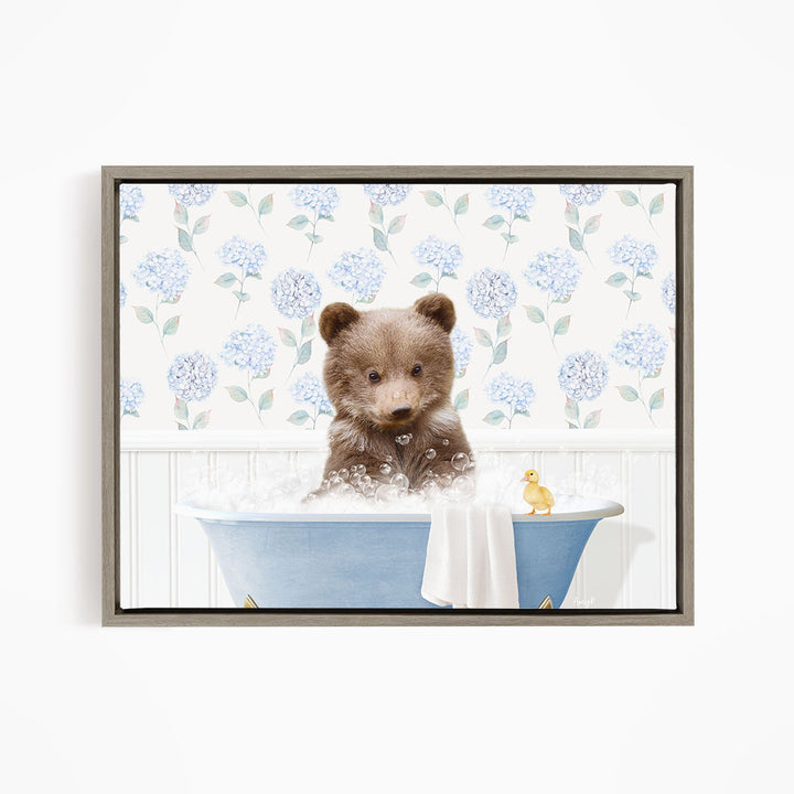 A brown bear sitting in a blue bathtub filled with bubbles, with a yellow duck floating nearby.
