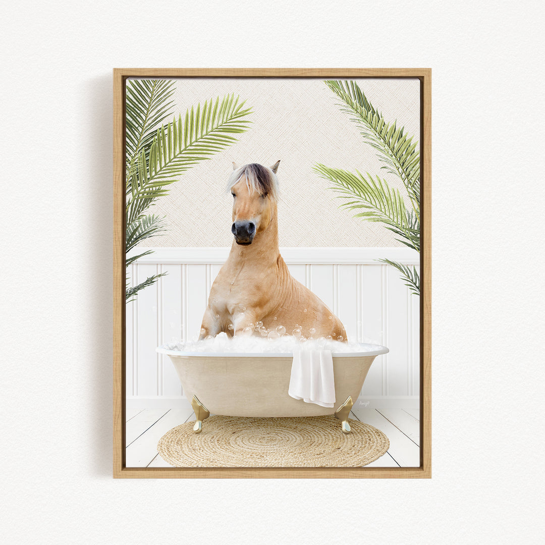 A light brown horse is sitting in a white bathtub filled with bubbles, surrounded by green palm leaves.