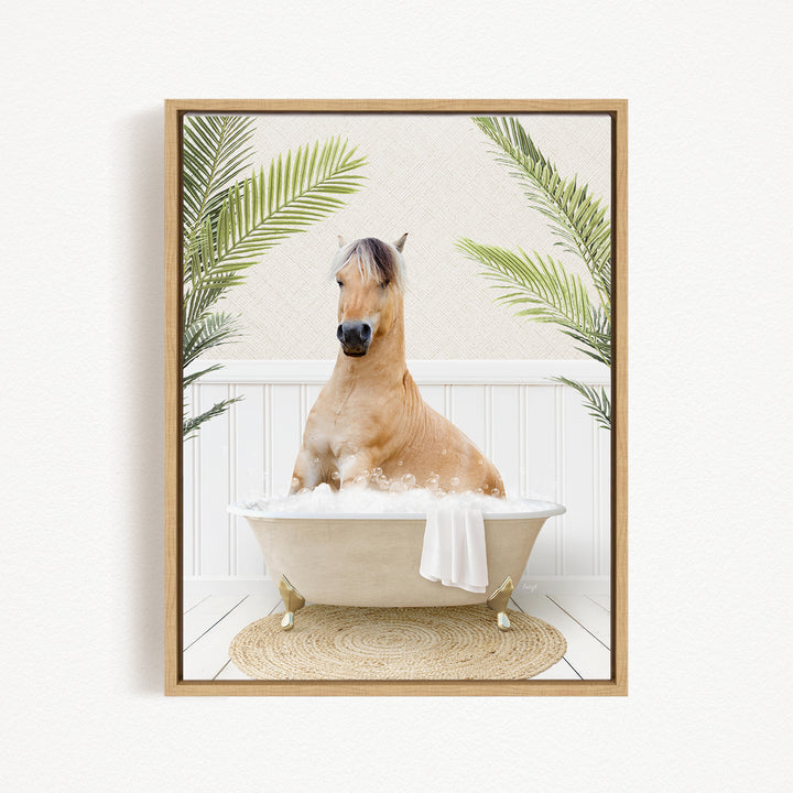 A light brown horse is sitting in a white bathtub filled with bubbles, surrounded by green palm leaves.