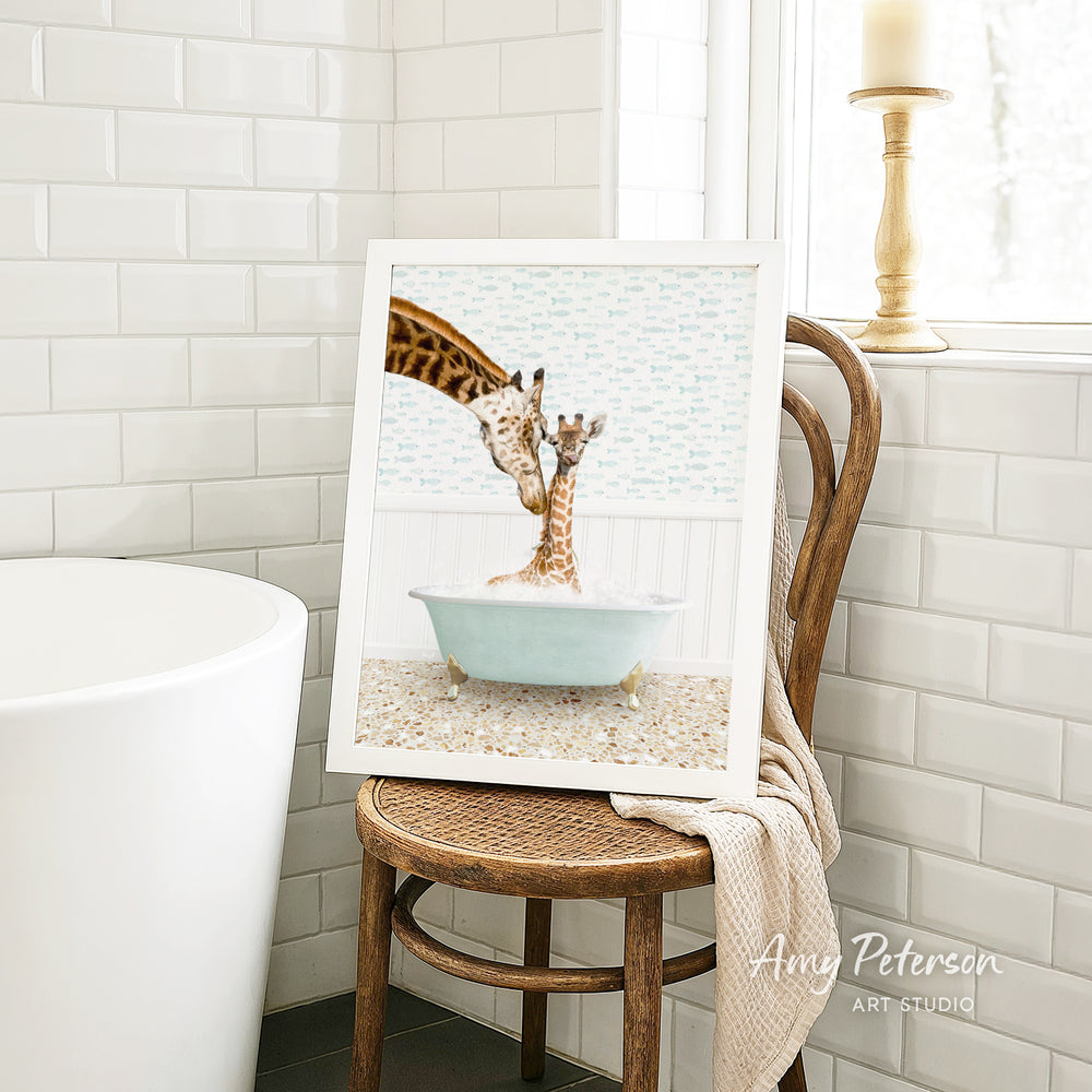 A framed image of two giraffes in a bathtub is displayed on a wooden chair in a bathroom setting.