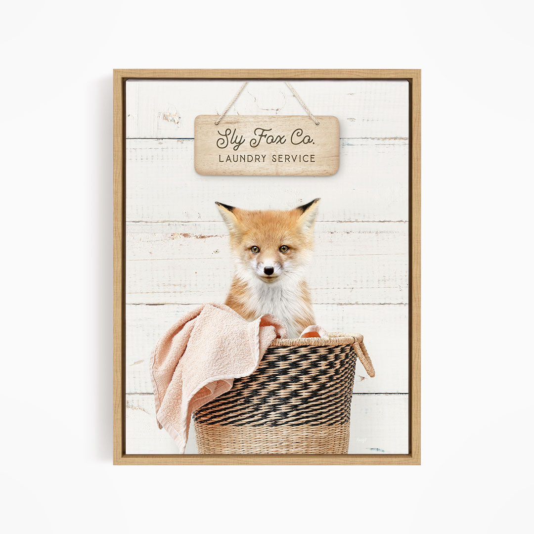 A young fox sits in a woven basket, with a sign above it that reads "Laundry Service".