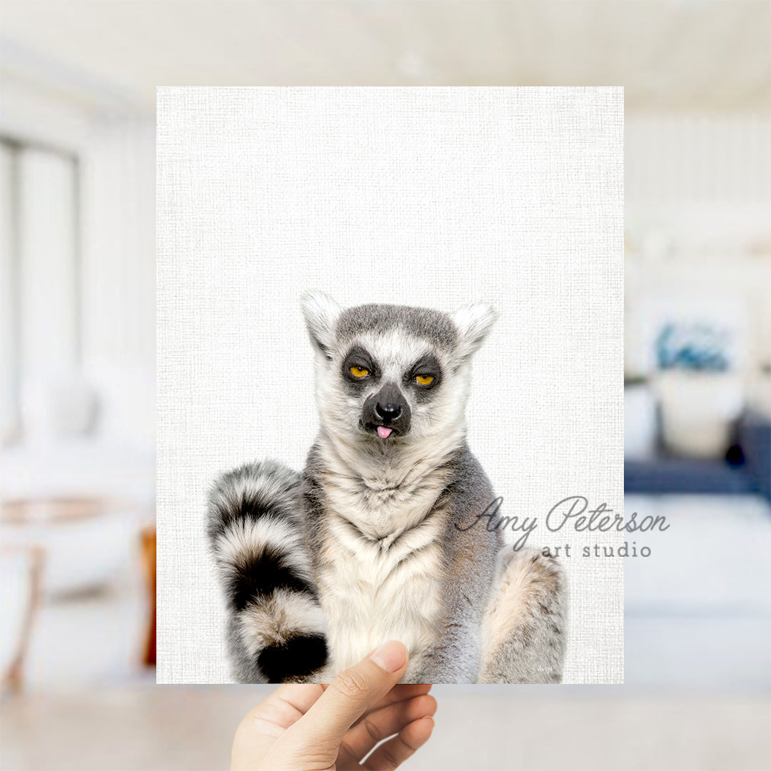 a hand holding a picture of a ring tailed lemur