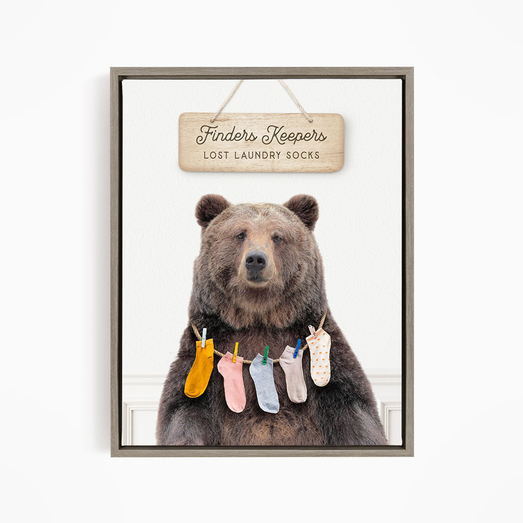 A wooden sign with the text "Finders Keepers" hangs above a bear wearing a pile of colorful socks.