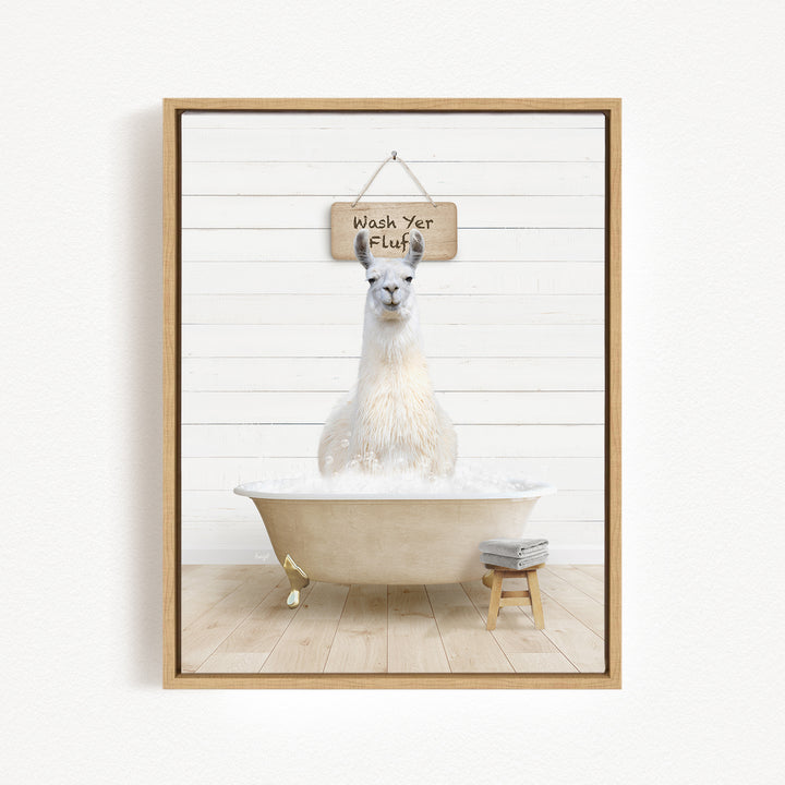 A white llama sitting in a bathtub, with a wooden sign above it that says "Wash Yer Fluff".