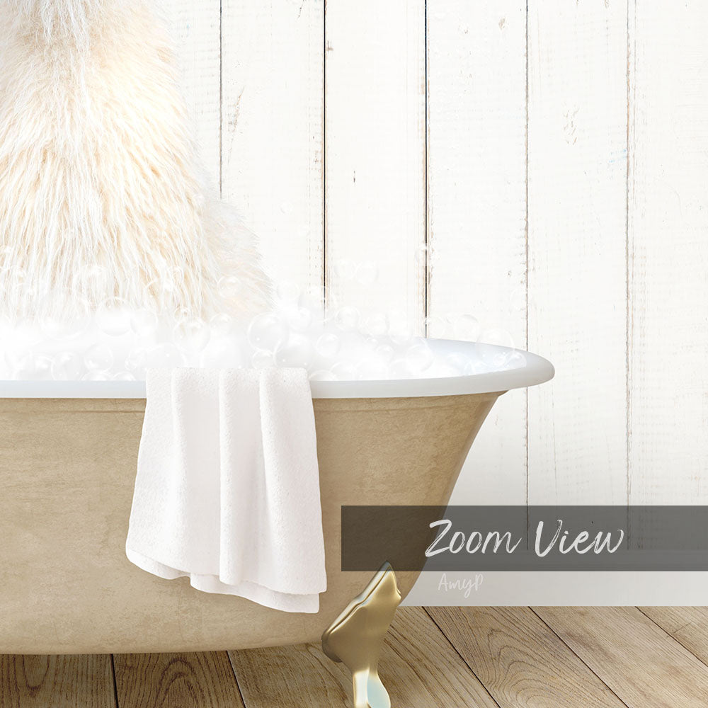 A white bathtub filled with bubbles, with a towel draped over the side and a wooden wall in the background.