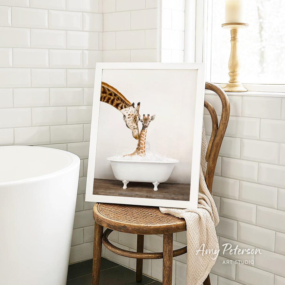 A framed image of a giraffe standing in a bathtub, with another giraffe inside the tub, is displayed on a wooden chair in a bathroom setting.