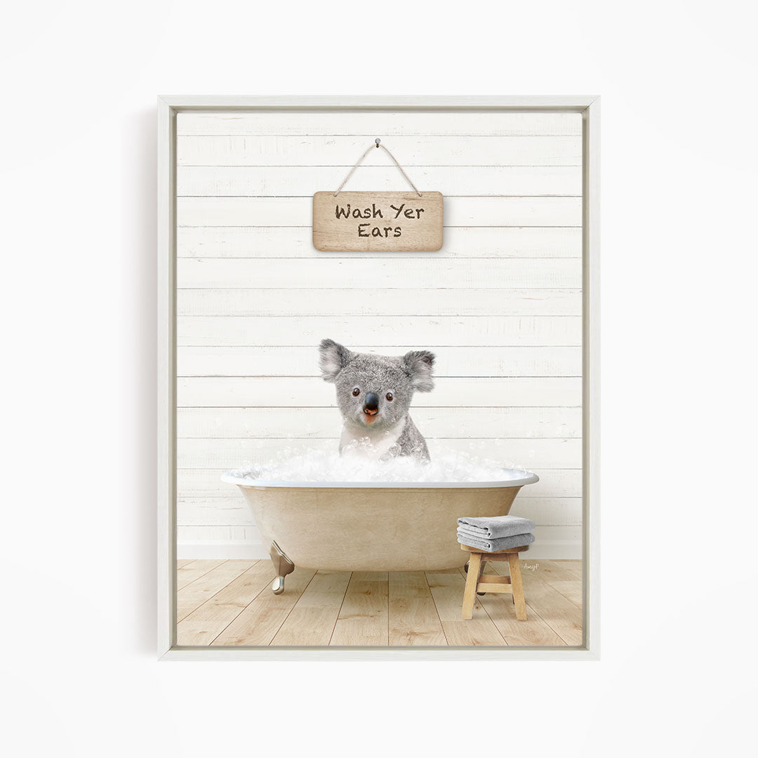 A koala bear sitting in a bathtub, with a sign above that says "Wash Your Ears".