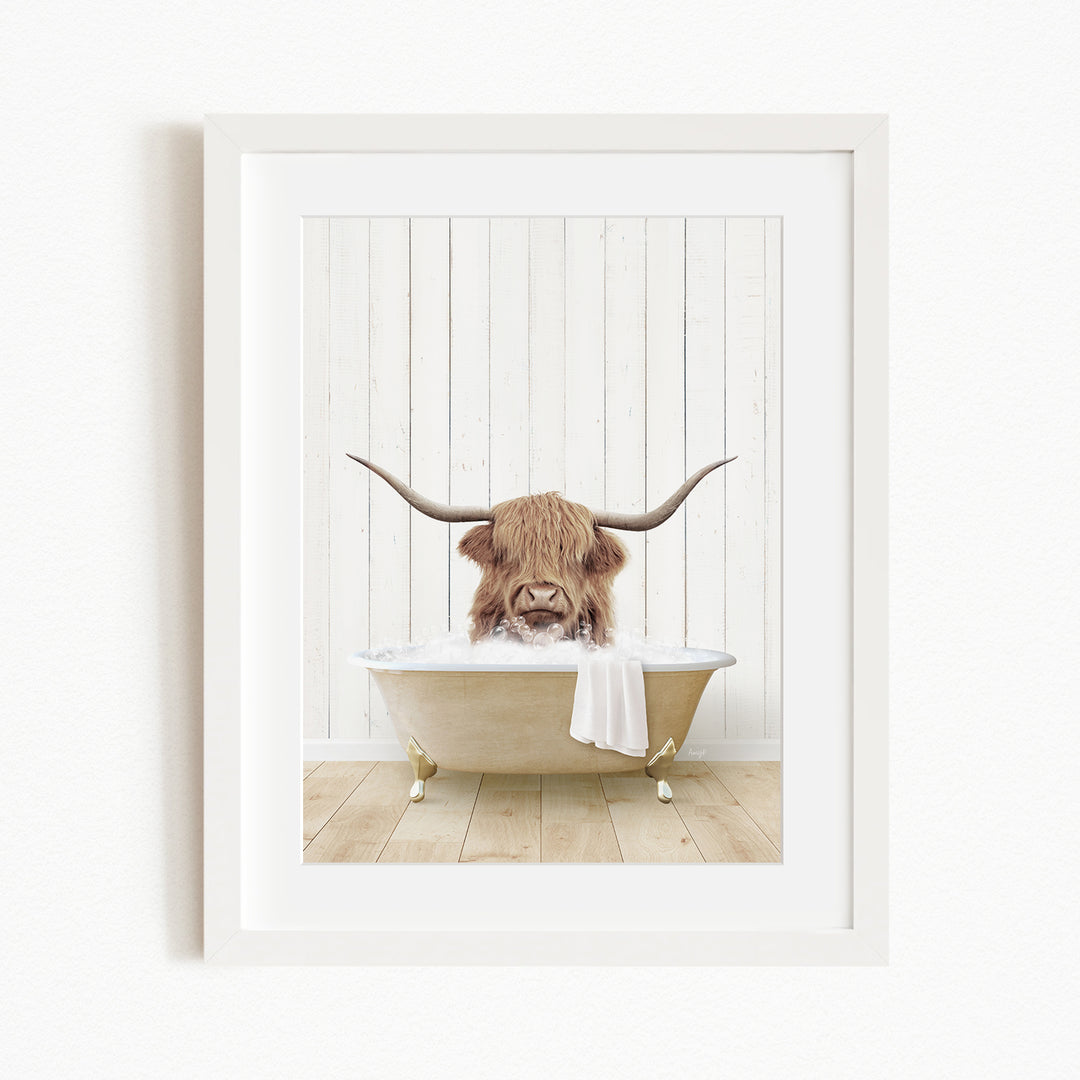 A framed image depicting a Highland cow with long horns sitting in a bathtub filled with water.