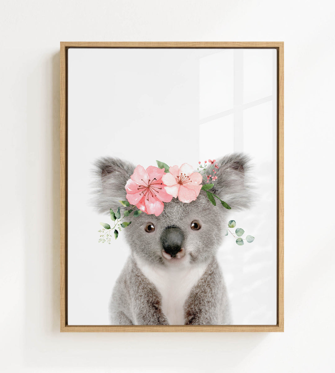 A framed image of a koala bear wearing a floral crown.