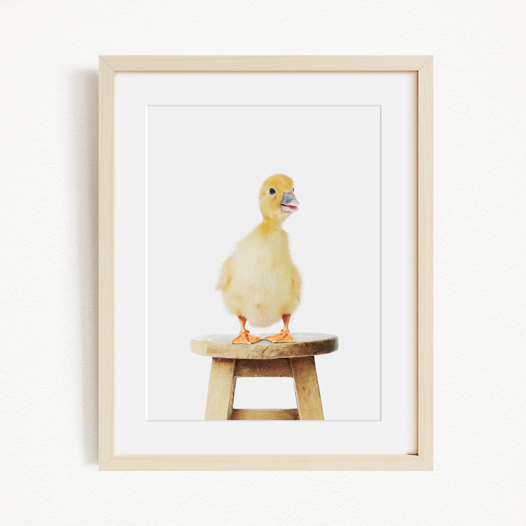 A small yellow duck standing on a wooden stool.