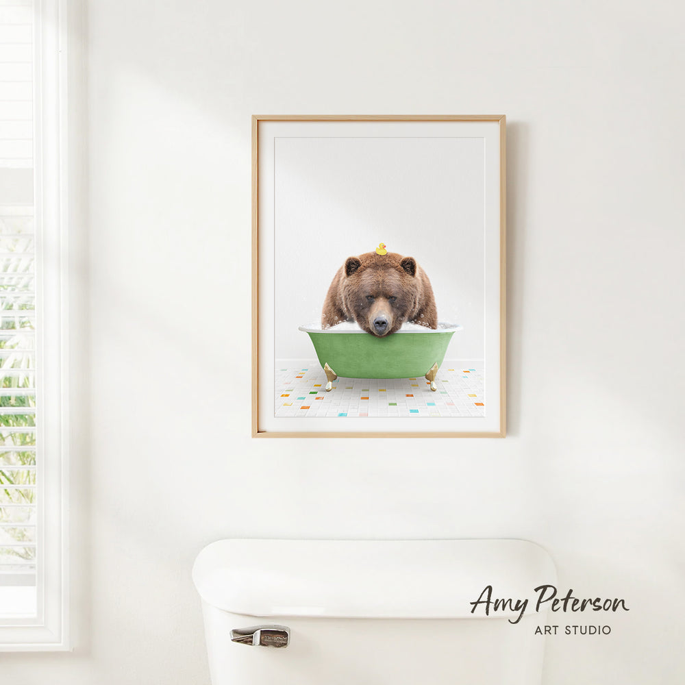 A framed image of a brown bear sitting in a green bathtub, with a yellow rubber duck floating in the water.
