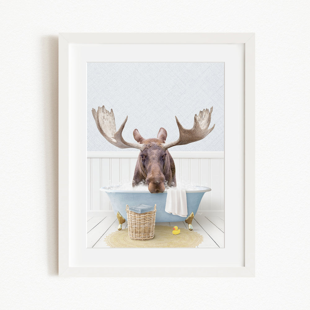 A moose with large antlers is sitting in a bathtub filled with water, surrounded by a basket of rubber ducks and a yellow rubber ducky.