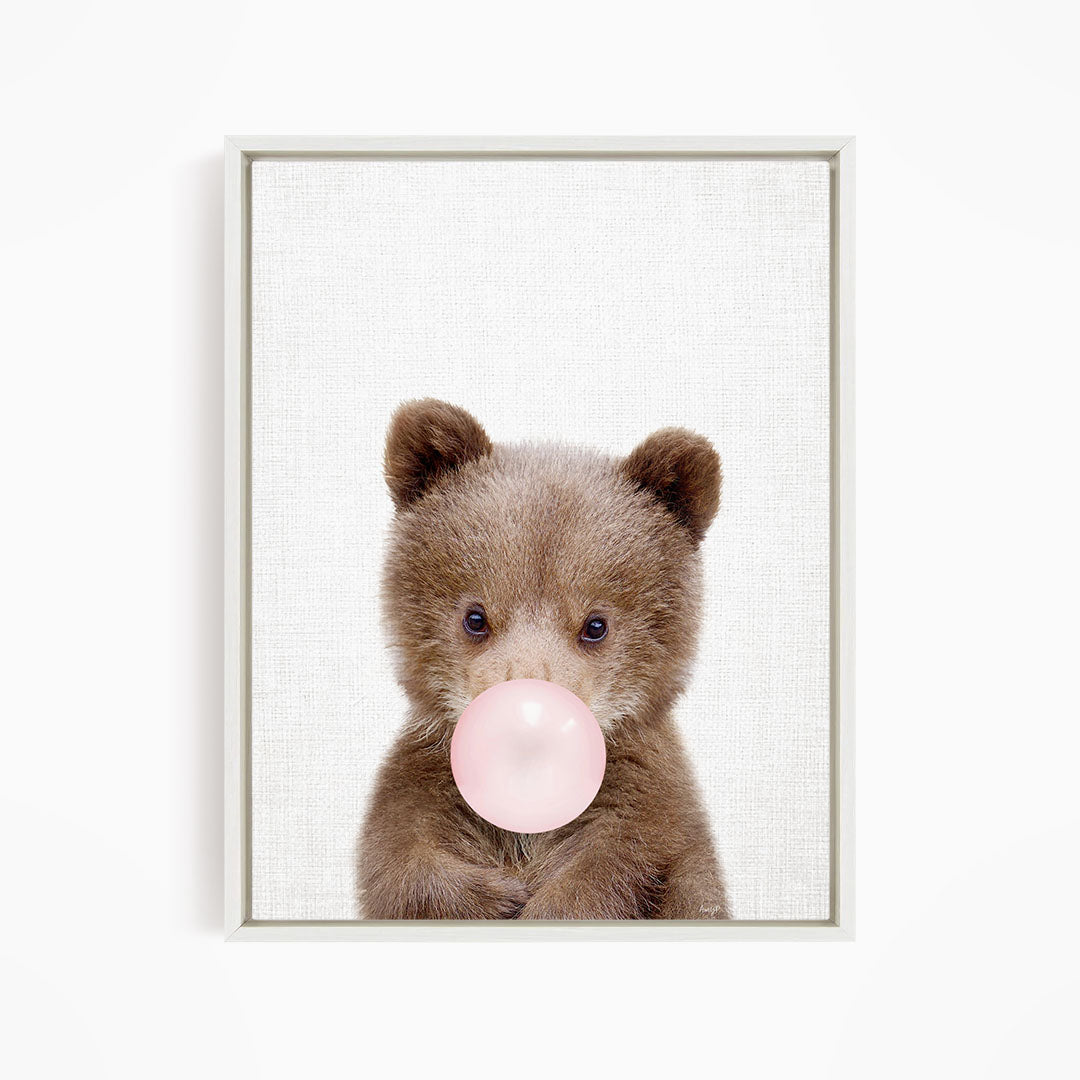 A cute brown bear is blowing a bubble with a pink bubble gum bubble.