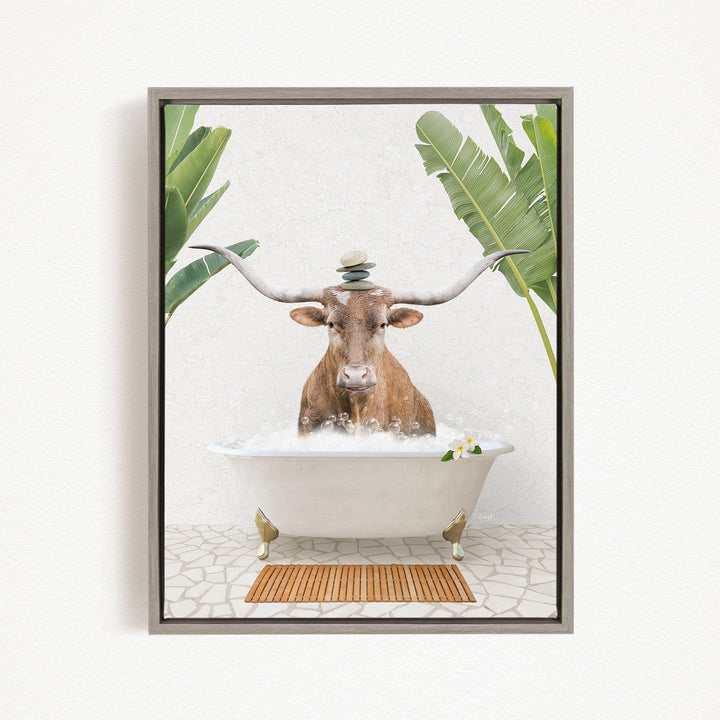 A brown cow with large horns is sitting in a white bathtub filled with bubbles, surrounded by green leaves and a wooden mat on the floor.