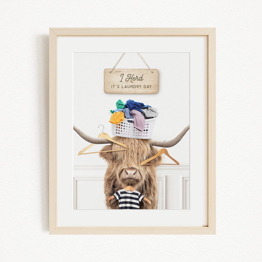 A framed image depicting a cow with a basket of laundry on its head, accompanied by a sign that reads "I hold it's laundry day".