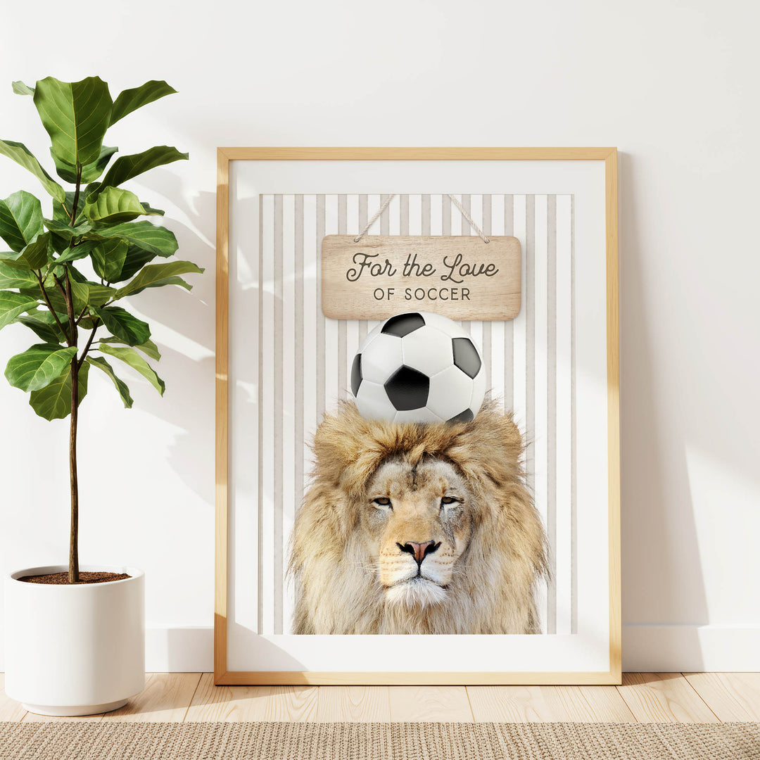 A framed poster featuring a lion with a soccer ball on its head, accompanied by a wooden sign that says "For the Love of Soccer".