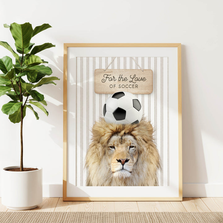 A framed poster featuring a lion with a soccer ball on its head, accompanied by a wooden sign that says "For the Love of Soccer".