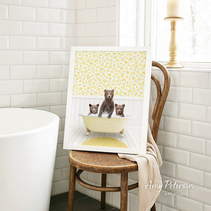 A framed image of three bears sitting in a bathtub, with a yellow floral pattern on the wall behind them.
