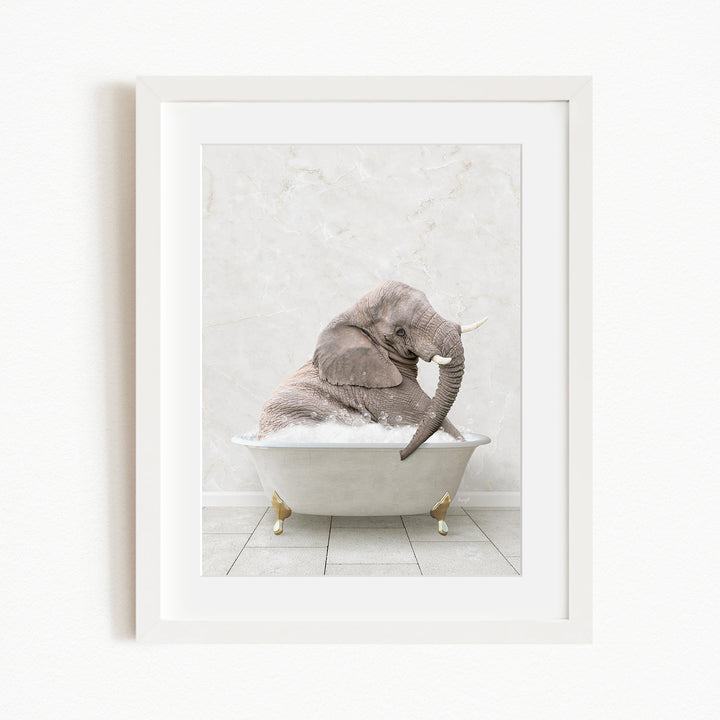 A gray elephant is sitting in a white bathtub, with its trunk raised and appearing to be enjoying the bath.