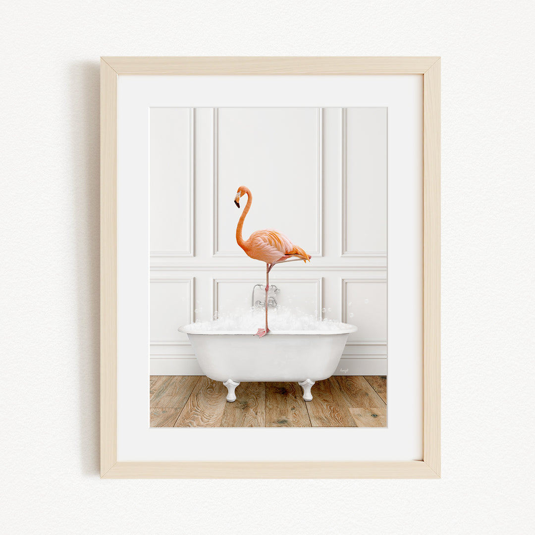 A framed image of a flamingo standing on the edge of a white bathtub filled with water.