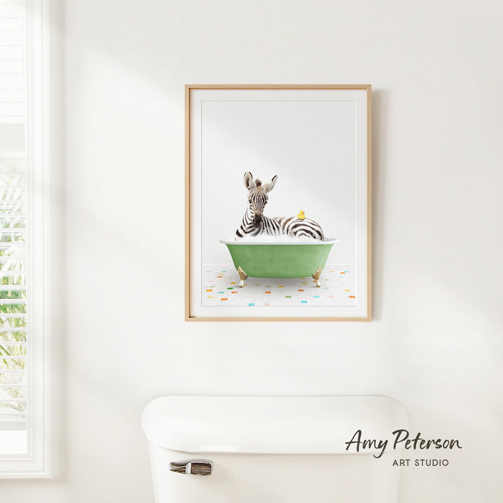 A framed print of a zebra sitting in a green bathtub, with a yellow bird perched on the zebra's head, is hanging on a white wall.